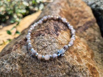 Stijlvolle armband gemaakt van prachtige, lichte natuurstenen kralen, gecombineerd met zilverkleurige ringetjes en een schattige schildpad bedeltje in het midden. Aan de andere kant vind je ons Descent logo-labeltje. Een classy armband die subtiel schitte